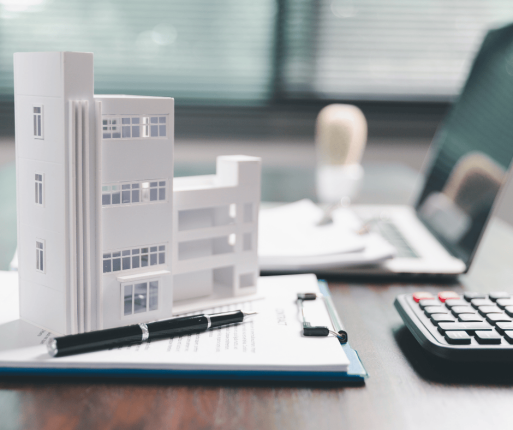 Maquette d’immeuble à revenus sur un bureau, illustrant l’achat d’un premier immeuble locatif au Québec.