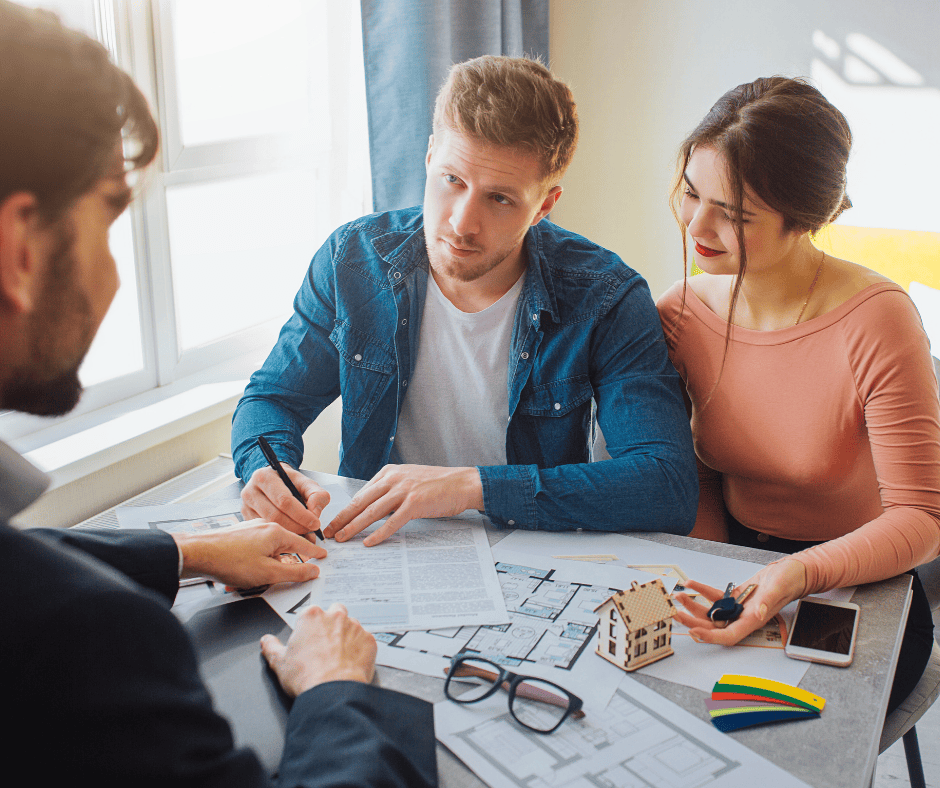 Couple rencontrant un professionnel pour comprendre les frais à prévoir lors de l’achat d’une propriété au Québec.