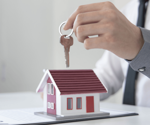 Main tenant des clés au-dessus d’une petite maison, représentant l’utilisation des REER pour acheter une première propriété.